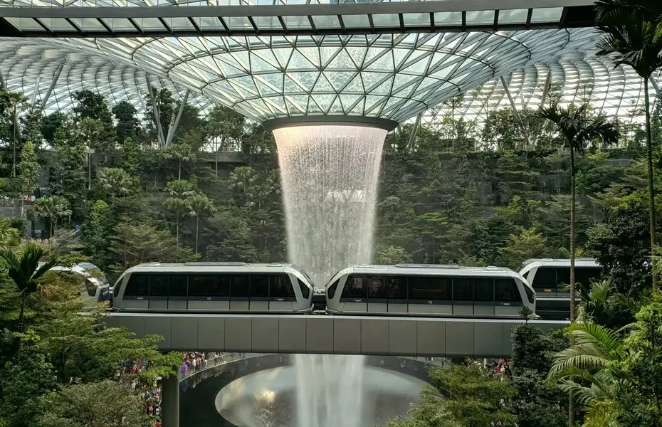 photo of inside a large glass building with trees - water feature and mono rail train